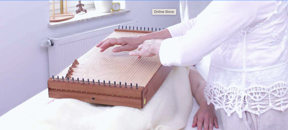 a woman playing feeltone monochord that is laying on top of a person | weplaywelltogether