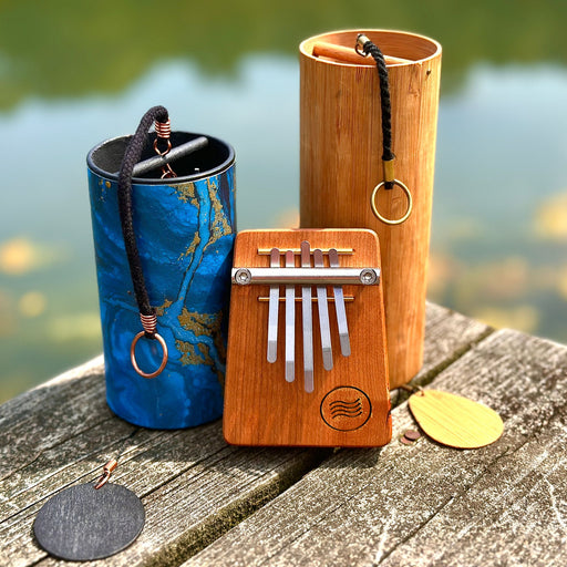 Twinkle Water Drop Bundle: KOSHI, ZAPHIR, B5 (432HZ) - Elemental Soundscapes Water Collection (D-minor) , two wind chimes and a Kalimba on a wooden platform above the water