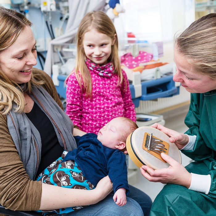 Music therapist Susann Kobus playing the Hokema Sansula for a mother and baby in a neonatal unit