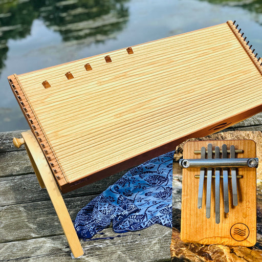 MONOLINA D - Elemental Soundscapes Water Collection (D-minor) sitting on a wooden dock in front of a lake with a Hokema B5 Kalimba |weplaywelltogether
