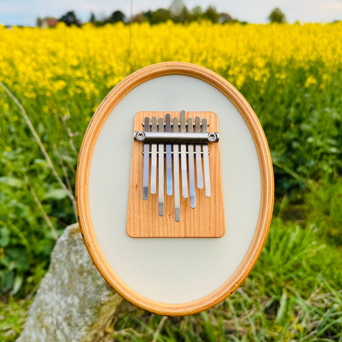 Hokema Sansula Renaissance kalimba in a field with yellow flowers | weplaywelltogether