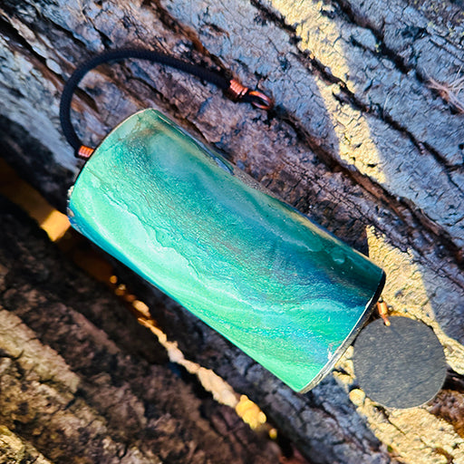 green colored Zaphir chime laying on the earth on a piece of bark  |Weplaywelltogether.