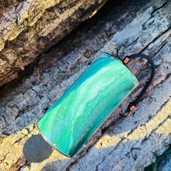 green colored Zaphir chime laying on the earth on a piece of bark  |Weplaywelltogether.