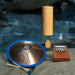 Zenko elemental Aqua tongue drum with mallets, Koshi Aqua chime and Hokema 9-tine Aqua kalimba on a rock in front of a river  | Weplaywelltogether