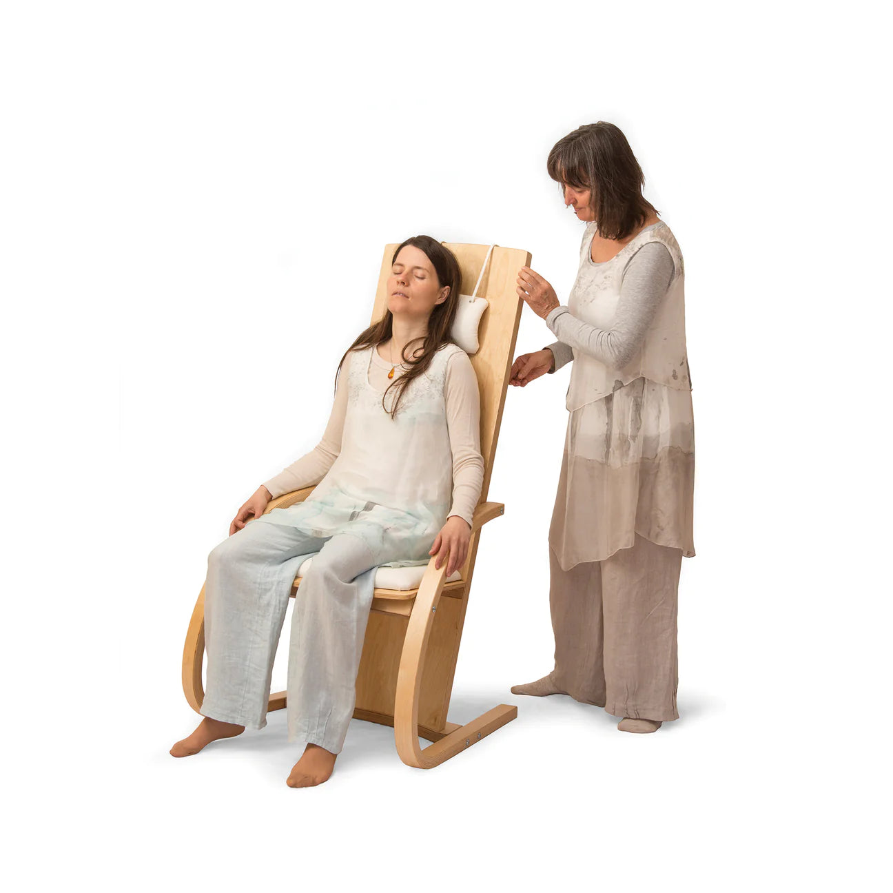 A woman sitting on a feeltone Monchair, a musical chair with strings attached to the back allowing full body experience of sound. Another woman is standing behind to chair and playing the strings. | weplaywelltogether