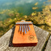 HOKEMA B5 KALIMBA - Elemental Soundscapes Water Collection (D-minor) sitting on a wooden bench in front of a lake